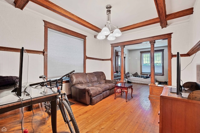 living area featuring beamed ceiling, light wood finished floors, and an inviting chandelier