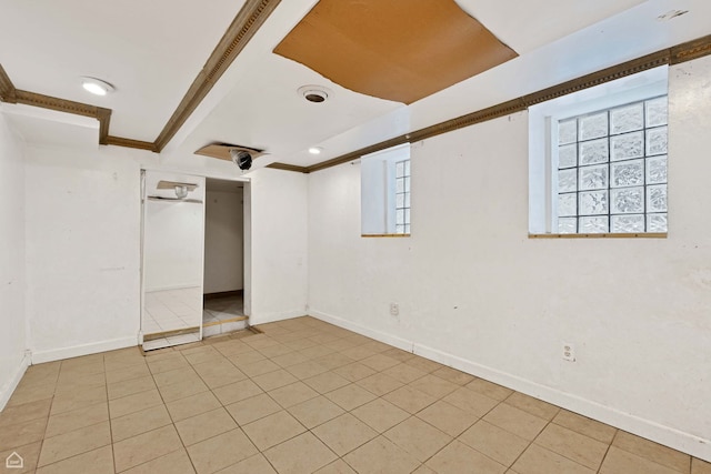 spare room featuring ornamental molding, baseboards, and light tile patterned floors