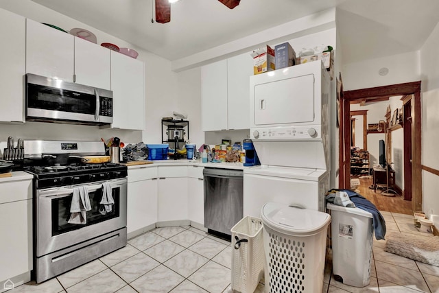 kitchen featuring stacked washer and dryer, light countertops, white cabinets, and appliances with stainless steel finishes