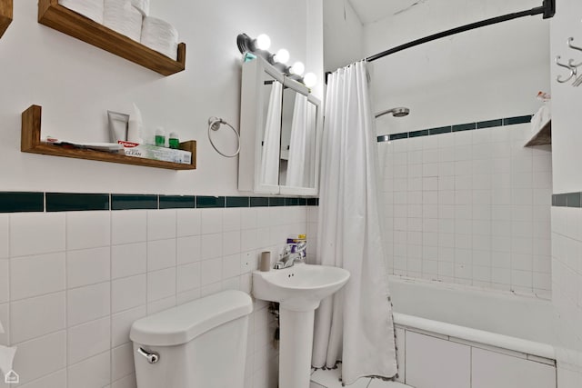bathroom with toilet, shower / bath combo, a sink, and tile walls