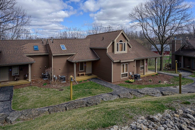 rear view of property featuring a yard, central air condition unit, and roof with shingles