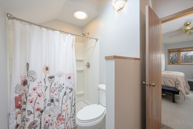 ensuite bathroom featuring connected bathroom, a shower with curtain, a ceiling fan, vaulted ceiling, and toilet