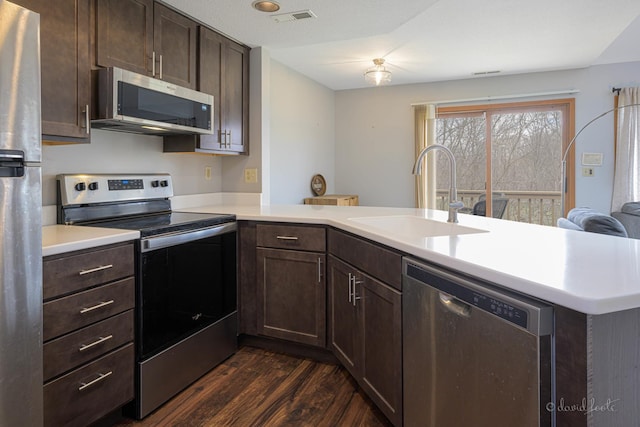 kitchen featuring a peninsula, visible vents, appliances with stainless steel finishes, light countertops, and a sink