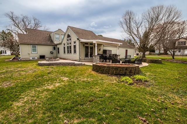 rear view of house with a yard, a patio area, and a fire pit