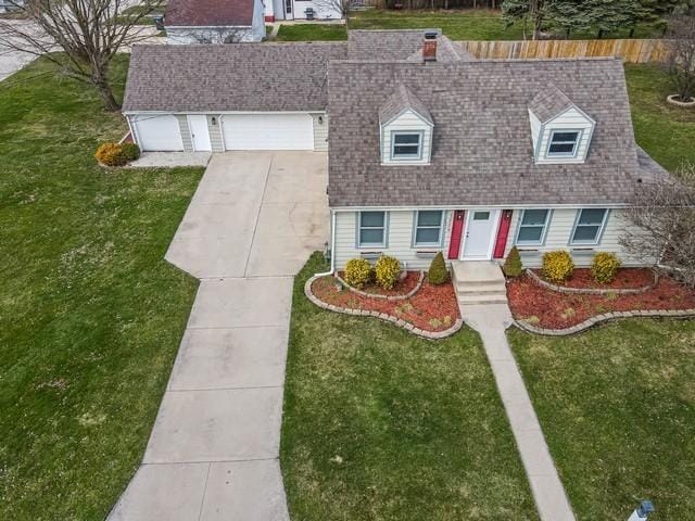 cape cod-style house featuring a front yard, concrete driveway, and roof with shingles