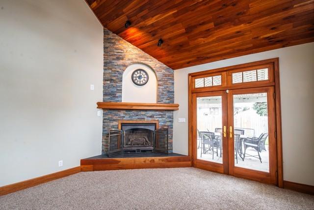 unfurnished living room featuring french doors, baseboards, wooden ceiling, and carpet floors