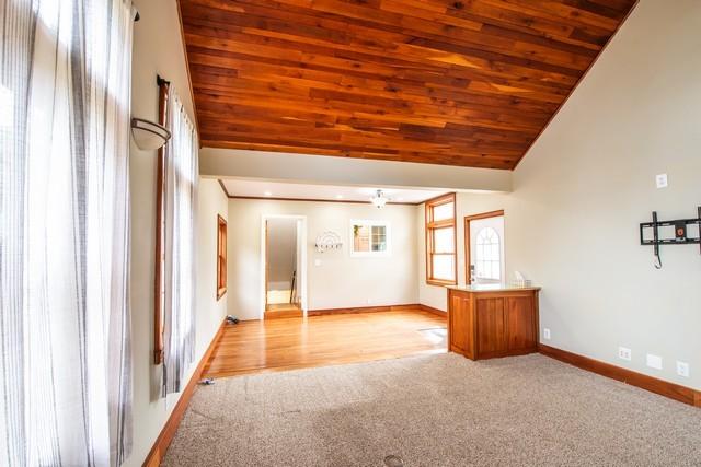 spare room featuring baseboards, light carpet, vaulted ceiling, and wood ceiling