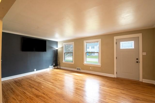 unfurnished living room featuring visible vents, light wood-type flooring, and baseboards