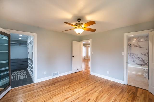 unfurnished bedroom with visible vents, baseboards, a ceiling fan, connected bathroom, and light wood-style flooring