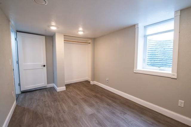 unfurnished bedroom with a closet, dark wood-style flooring, and baseboards