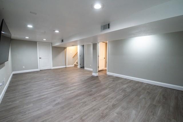 finished basement with visible vents, baseboards, recessed lighting, stairway, and wood finished floors