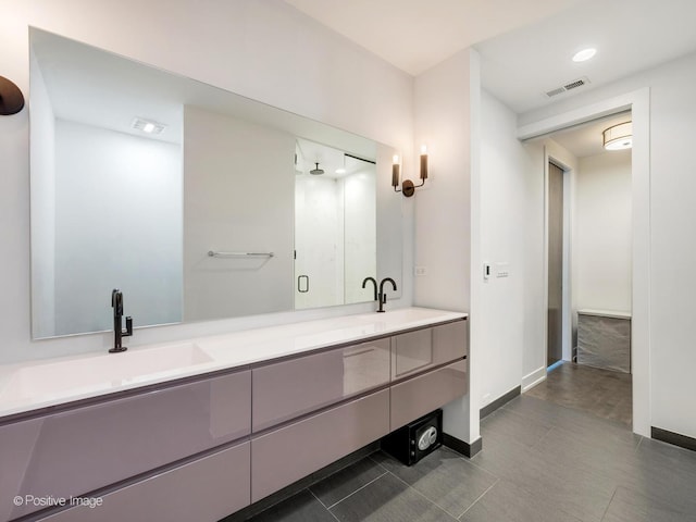 full bath with a sink, visible vents, baseboards, and double vanity