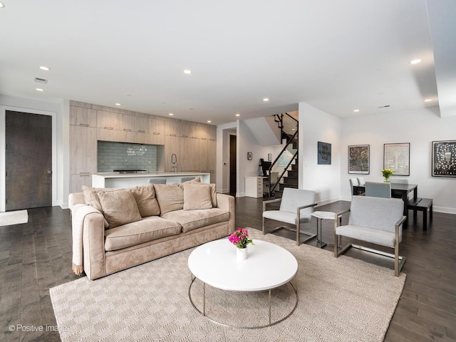 living room with dark wood-style flooring, visible vents, recessed lighting, and stairs