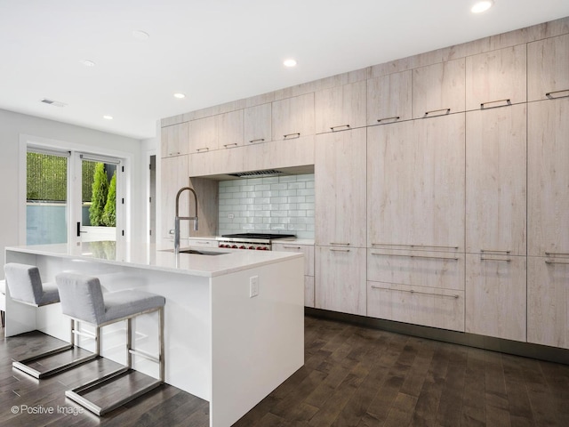 kitchen with visible vents, modern cabinets, a sink, a kitchen bar, and dark wood-style floors