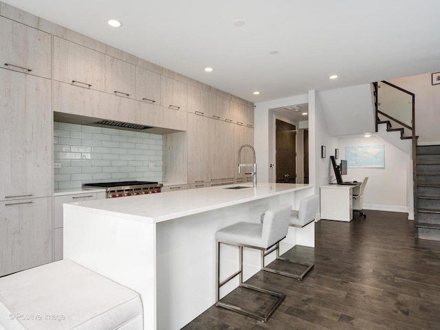 kitchen with modern cabinets, stove, dark wood-style flooring, light countertops, and a sink