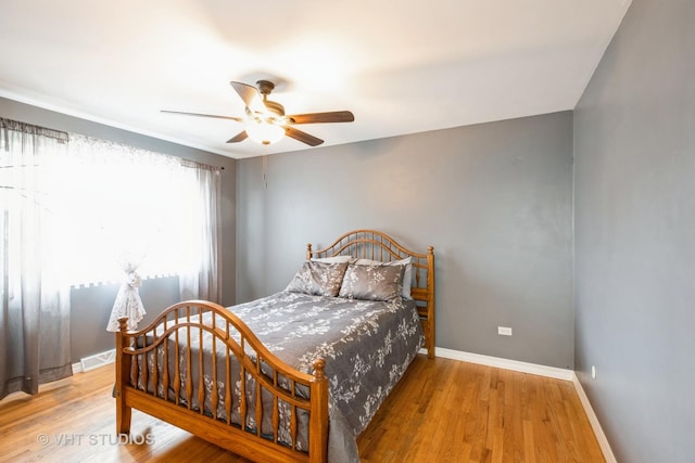 bedroom with visible vents, baseboards, a ceiling fan, and wood finished floors