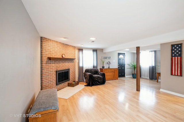 living room with a fireplace, light wood-style flooring, and baseboards