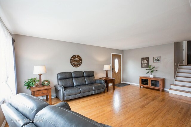 living room with stairway, baseboards, wood finished floors, and a healthy amount of sunlight
