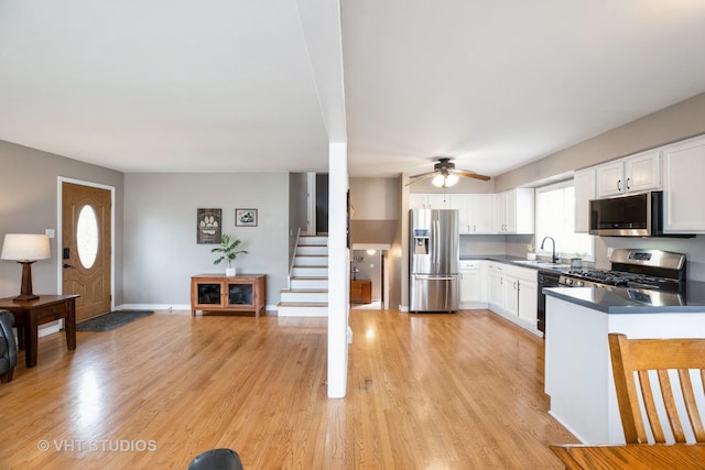 kitchen featuring light wood-type flooring, a ceiling fan, white cabinetry, a sink, and stainless steel appliances