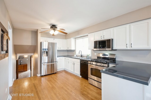 kitchen featuring stainless steel appliances, a sink, a ceiling fan, and dark countertops