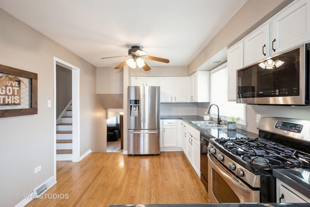 kitchen featuring ceiling fan, light wood-style flooring, white cabinets, a sink, and stainless steel appliances