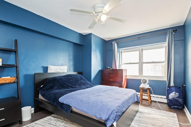 bedroom featuring ceiling fan, a baseboard radiator, baseboards, and wood finished floors