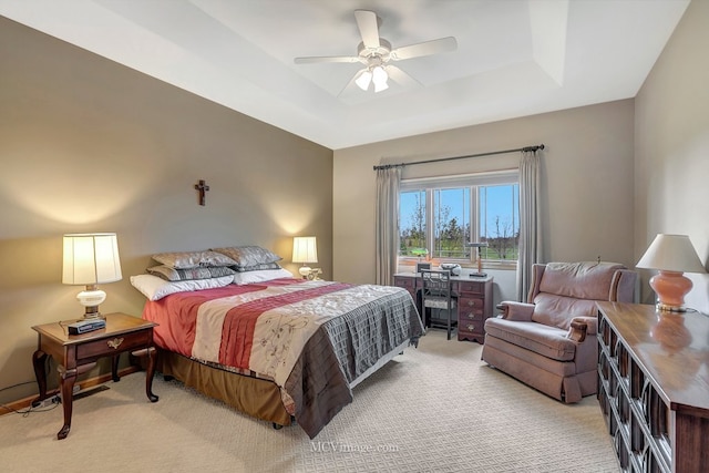 bedroom featuring ceiling fan, light colored carpet, and a raised ceiling