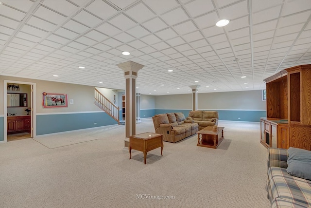 carpeted living area featuring baseboards, stairway, decorative columns, and recessed lighting