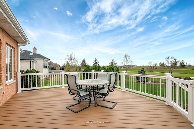 deck featuring outdoor dining space and a lawn