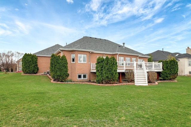 back of property with a yard, stairway, brick siding, a wooden deck, and roof with shingles