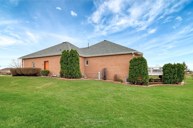 view of property exterior with brick siding, a shingled roof, and a lawn