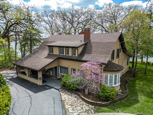 1046 N Hainesville Rd, Round Lake Beach, IL 60073 - view of home's exterior with a shingled roof, stucco siding, a chimney, and a lawn