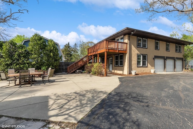 1046 N Hainesville Rd, Round Lake Beach, IL 60073 - back of house featuring stairway, stucco siding, a deck, an attached garage, and driveway