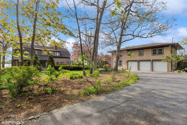 1046 N Hainesville Rd, Round Lake Beach, IL 60073 - view of front of home featuring stucco siding, a garage, asphalt driveway, and a chimney