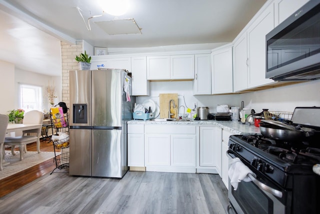 732 N Dearborn Ave, Kankakee, IL 60901 - kitchen featuring light wood-style floors, appliances with stainless steel finishes, a sink, and white cabinets