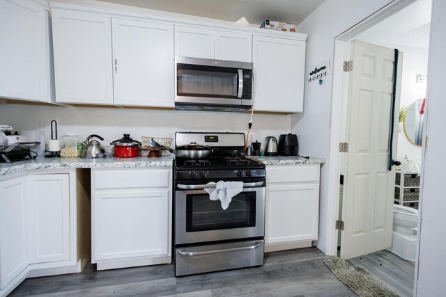 732 N Dearborn Ave, Kankakee, IL 60901 - kitchen featuring appliances with stainless steel finishes, light wood finished floors, light stone counters, and white cabinets