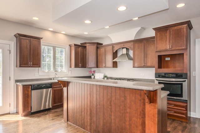 6433 Davidson Ct, Gurnee, IL 60031 - kitchen featuring appliances with stainless steel finishes, wall chimney range hood, wood finished floors, a kitchen island, and recessed lighting