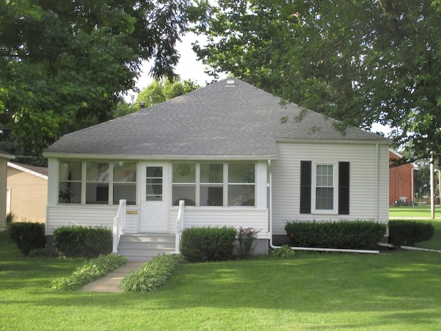 ranch-style house with a front yard, a shingled roof, and a sunroom