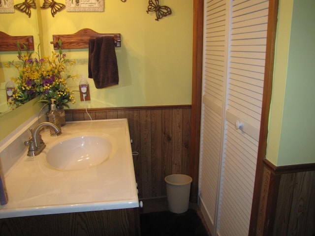 bathroom featuring wood walls, vanity, and a wainscoted wall