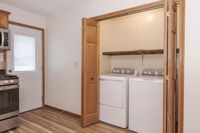 laundry room featuring light wood-type flooring, washer and clothes dryer, baseboards, and laundry area