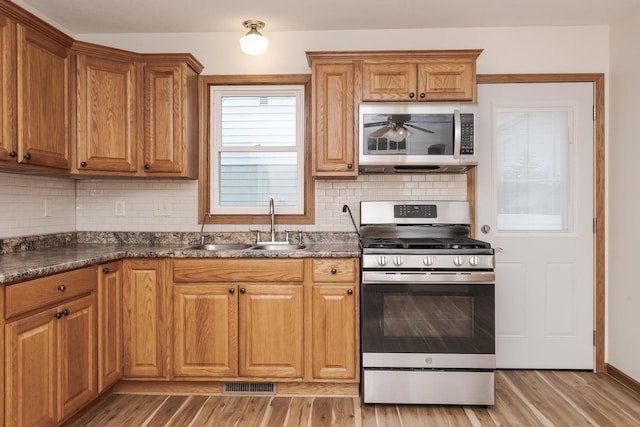 kitchen featuring dark countertops, stainless steel appliances, visible vents, and a sink