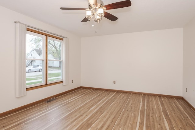 spare room featuring light wood-style floors, visible vents, a ceiling fan, and baseboards