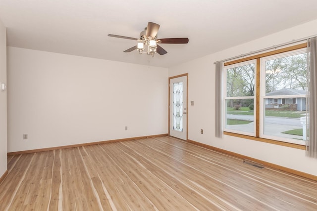 empty room featuring light wood-style flooring, visible vents, and baseboards
