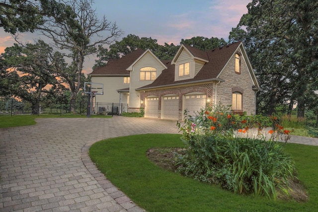 41W050 Stoneridge Ln, Elgin, IL 60124 - french country style house featuring curved driveway, fence, stone siding, roof with shingles, and a front lawn