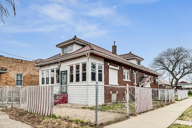 7658 S Laflin St, Chicago, IL 60620 - view of home's exterior featuring a tiled roof, a chimney, brick siding, and a fenced front yard