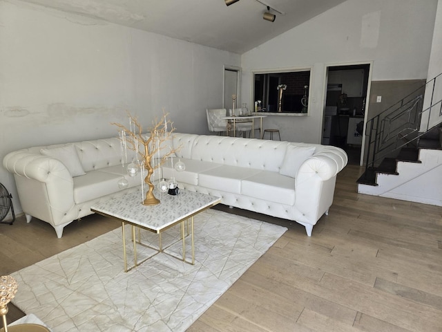 living room featuring wood finished floors, lofted ceiling, and stairway