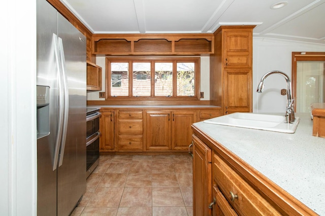 kitchen featuring crown molding, a sink, brown cabinetry, stainless steel appliances, and light countertops