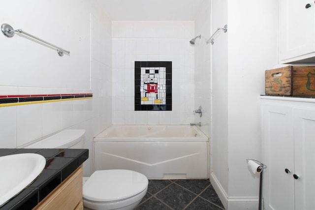 bathroom with tile patterned flooring, bathing tub / shower combination, toilet, vanity, and tile walls