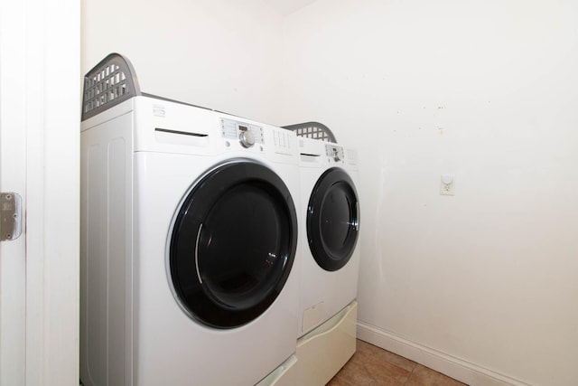 laundry area featuring baseboards, washer and clothes dryer, laundry area, and light tile patterned flooring