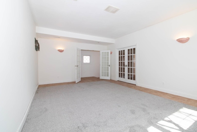 carpeted empty room featuring baseboards and french doors